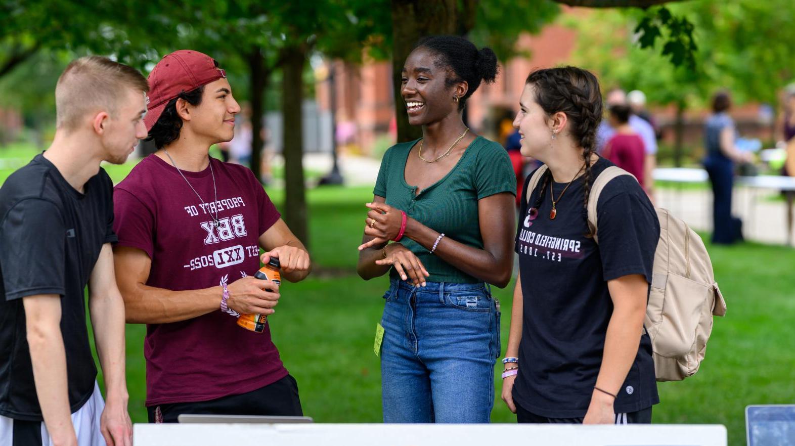 Students at a club fair talking on Naismith green